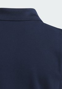 Mörkblå polo med strukturerad tyg, med klassisk krage och korta ärmar, som framhäver rena sömmar och inga synliga logotyper.