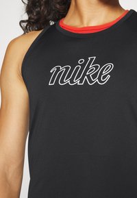 Zwart sport tanktop gemaakt van gladde stof, met een rode halslijn en een opvallend wit "nike" logo op de borst.