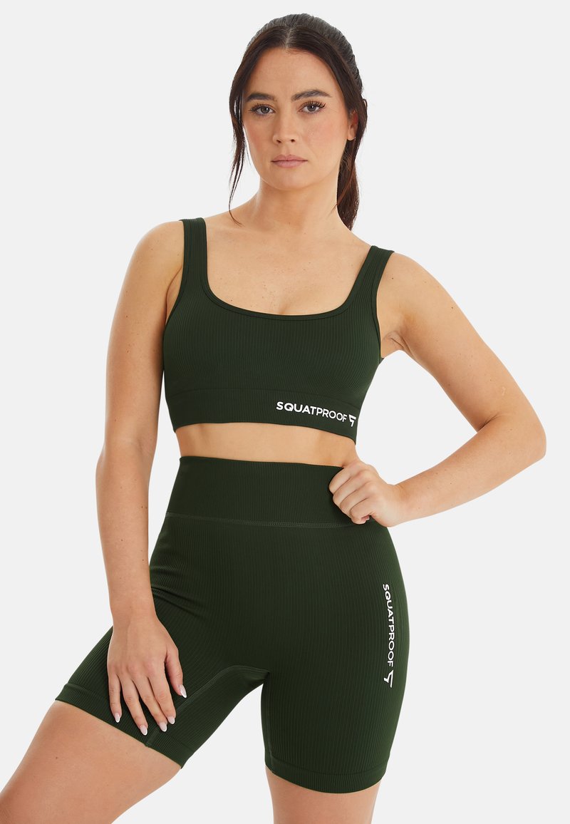 Donkergroene geribbelde sportcrop top en high-waisted shorts met witte "SQUATPROOF" tekst op de tailleband en dij. Zacht, rekbaar materiaal.