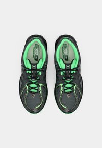 Chaussures de sport noires avec des accents vert néon, tige en mesh, col rembourré et design à lacets. Caractéristiques d'une surface texturée et d'une semelle en caoutchouc.