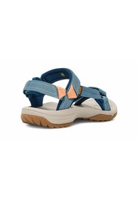 Sandalias exteriores azules con correas ajustables, suave acolchado y una robusta suela de goma color marrón; cuenta con acentos naranjas y tela texturizada.