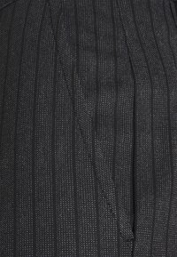 Close-up of dark fabric with vertical textured stripes and a subtle glossy pattern.