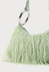 Zielona torebka z futerkiem z imitacji futra, z zaokrąglonym srebrnym metalowym uchwytem w kształcie pierścienia oraz teksturowaną, puszystą powierzchnią. Regulowany pasek ze skóry w jasnym zielonym kolorze.