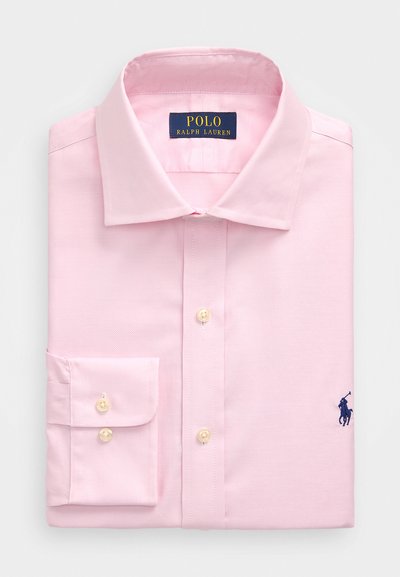 Camisa de vestir rosa claro, dobrada. Apresenta um colarinho tradicional, fecho por botões e mangas longas com punho. Logótipo em bordado azul-marinho no peito.