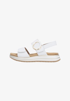 Sandalia blanca de punta abierta con suela acolchada beige, correa ajustable en el tobillo con una hebilla grande dorada y suela exterior de goma texturizada.