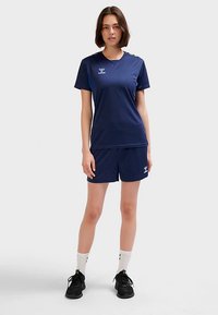 Granatowy strój sportowy składający się z krótkiego topu i szortów wykonanych z materiału odprowadzającego wilgoć, z logo i kontrastującymi akcentami.
