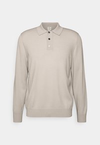 Beige långärmad polo t-shirt, tillverkad av mjukt tyg, med en klassisk krage, tre-knappsknäppning och ribbade ärmslut.