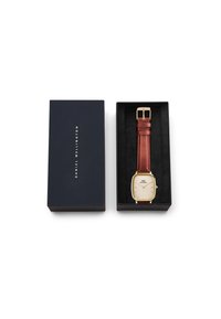 Gold rectangular watch with a cream dial and brown leather strap, presented in a navy box with a black interior.