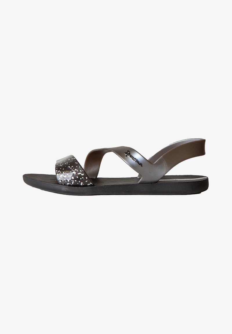 Sandali neri con un modello lucido a pois sulla fascetta, una zona toe ampia e una soletta imbottita. Presentano una fascetta sul tallone flessibile.