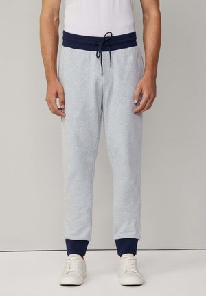 Graue Sweatpants mit einem marineblauen Bund und Bündchen. Kordelzug an der Taille, taillierte Form, aus weichem Material gefertigt. Lässiger Stil.