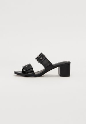 Black leather block-heel sandals feature two wide straps with rectangular buckles, open toe design, and a smooth, textured finish.