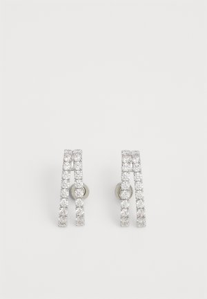 Silver earrings with two curved, interlocking lines. Each line is adorned with small clear stones, creating a sparkling effect.