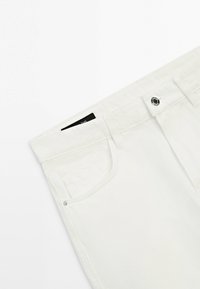 Jean en denim blanc au niveau de la taille avec poche avant, passants de ceinture et fermeture par bouton métallique sur fond blanc.