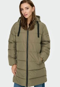Pufasta jakna u maslinasto zelenoj boji s kapuljačom, prednjim zatvaračem, crnim špagama i horizontalnim šavovima. Ima bočne džepove i srednju dužinu.