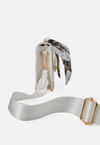 Petit sac rectangulaire en matière texturée gris clair, avec des ferrures dorées et une bandoulière grise amovible. Comprend un foulard décoratif à motifs.