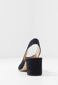Námořnické modré semišové slingback podpatky s blokovým podpatkem, zaoblenou špičkou a prošívaným detailem na zadním popruhu. Hladká vnitřní úprava.