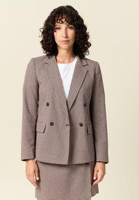 Kaksirivinen bleiseri ruskeassa ja valkoisessa houndstooth-kuosissa, jossa on leikattu kaulus, kaksi taskua ja mustat napit.