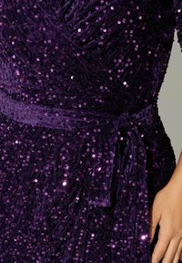 Purple dress made of soft fabric adorned with shiny, round sequins, featuring a wrap design and a tied belt detail.