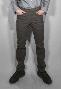 Chino verde scuro con vestibilità slim, texture liscia e chiusura frontale con bottoni. Abbinati a scarpe da ginnastica nere con suola ammortizzata.