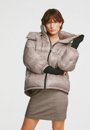 Padded jacket w kratę w odcieniach beżu i brązu, z wysokim kołnierzem, czarnymi dzianinowymi mankietami oraz zapięciem na zamek z przodu.