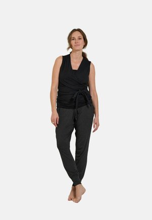 Black wrap top with a tied waist, paired with dark gray tapered joggers. Soft fabric, sleeveless design, casual fit, and minimalistic style.