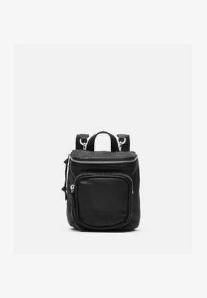 Sac à dos compact en cuir texturé noir avec poche zippée avant, poignée supérieure et bretelles réglables sur fond clair uni.