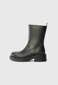 Black ankle boots made of synthetic material. Features a smooth finish, round toe, and a chunky heel with a rear pull tab for easy wear.