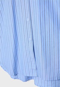 Tissu de chemise bleu avec fines rayures verticales noires et blanches, doté de deux boutons blancs sur la patte de boutonnage avant.