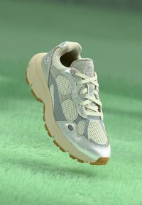 Lätt sneaker med ett överdel i mesh med silverdetaljer, texturerade grå överlägg och en kraftig beige sula. Utformad för komfort.