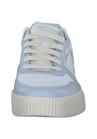Baskets Skechers blanches et bleu clair avec un dessus en cuir lisse, des lacets blancs et une semelle blanche nervurée. Détail du logo doré sur le côté.