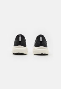 Black athletic shoes with a textured upper, cushioned white midsole, and black outsole. Features a rear pull tab and minimalist design.
