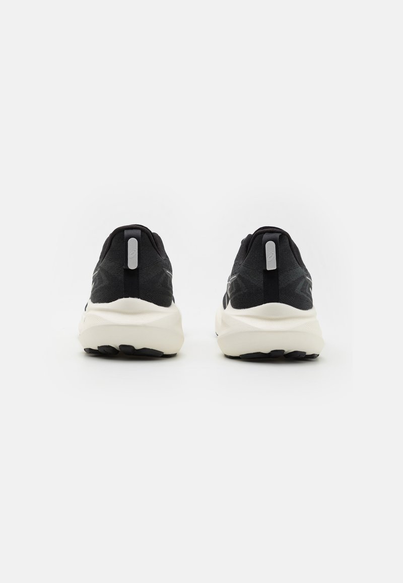Zapatillas deportivas negras con parte superior texturizada, mediasuela blanca acolchada y suela negra. Presenta una pestaña trasera y un diseño minimalista.