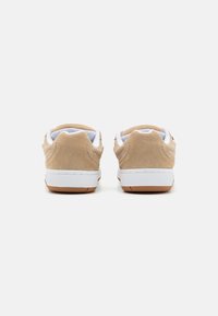 Adidași din suede, de culoare bej, cu accente albe și o talpă din cauciuc texturat. Dispun de o guler căptușit și un design minimalistic în spate.