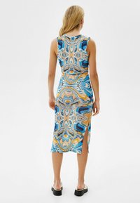 Sukienka bodycon bez rękawów z niebieskim, pomarańczowym i kremowym abstrakcyjnym wzorem, do kolan, z bocznym rozcięciem i miękkim, elastycznym materiałem.