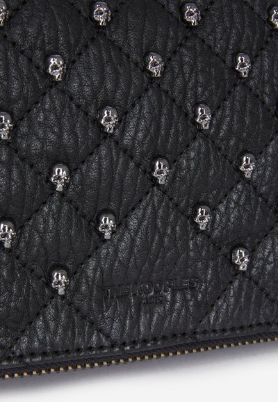 Clutch in pelle nera trapuntata con decorazioni in argento a forma di teschio. Superficie testurizzata con un motivo leggermente in rilievo e dettaglio del logo.