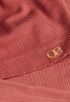 Tissu côtelé dans une teinte corail chaud, avec un accent logo doré subtil. La texture met en évidence un motif distinct de lignes surélevées.