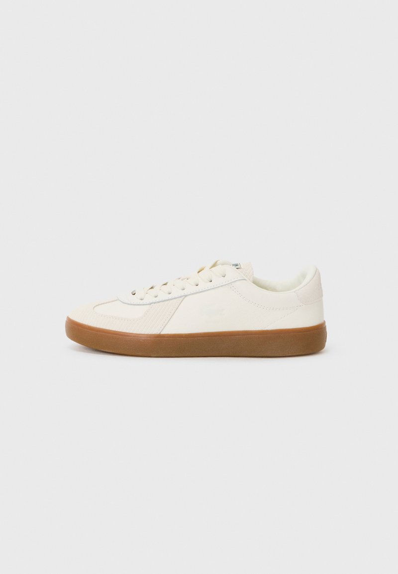Sneaker v kremni barvi z teksturirano zgornjico, okroglo konico, vezalnim dizajnom in rjavim gumijastim podplatom. Ima diskretne podrobnosti z logotipom.