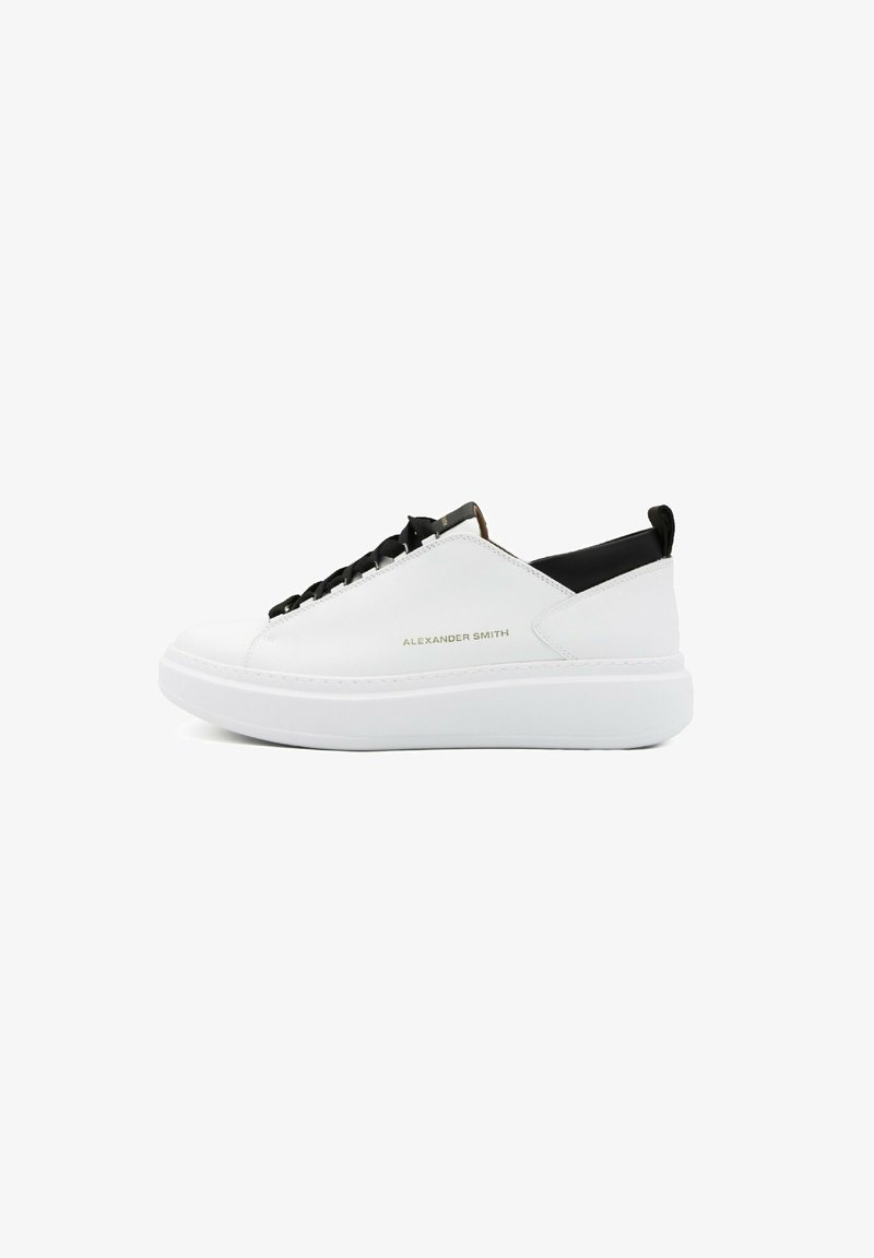 Sneakers bianchi in pelle a bassa altezza con un tallone testurizzato nero, lacci neri, suola elevata bianca e branding in rilievo sul lato.