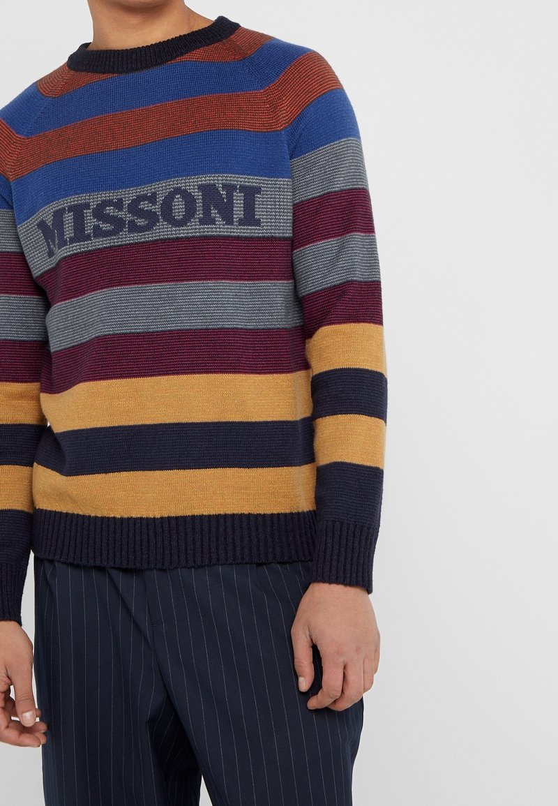 Gestreepte gebreide trui met gedurfde kleuren: rood, blauw, grijs, bordeauxrood en geel. Gestructureerde stof met het "MISSoni"-logo op de borst.