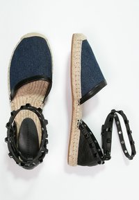 Espadriller med ovandel i denim, svarta läderdetaljer och flätade jutesulor. Inkluderar avtagbar svart rem med nitar.