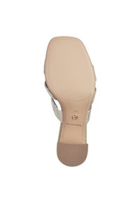Light beige sandal with a textured upper, open-toe design, and a slip-resistant rubber outsole. Features a curved heel and branding.