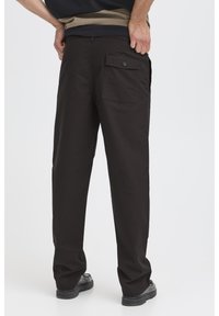 Pantalones negros hechos de tela ligera, con un solo bolsillo trasero con botón. Las piernas son de corte recto para un ajuste cómodo.