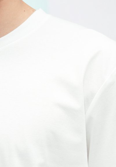 Weißes Baumwoll-T-Shirt mit klassischem Rundhalsausschnitt und kurzen Ärmeln, mit glatter Textur und minimalistischem Design.
