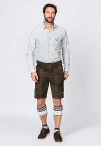Grün-weißer karierteter Langarmhemd mit braunen Lederhosen, verziert mit Knopfdetails, knielangen Beinlingen und dunklen Schuhen.