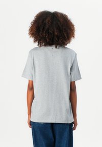T-shirt gris à manches courtes en coton. Il présente une coupe décontractée avec une coupe droite et une petite étiquette logo dans le haut du dos.