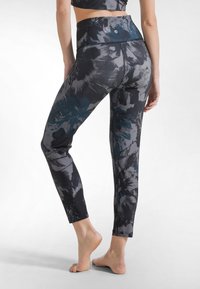 Leggings neri a vita alta con motivo floreale in grigio e verde acqua. Realizzati in tessuto elasticizzato, con finitura liscia e design aderente.