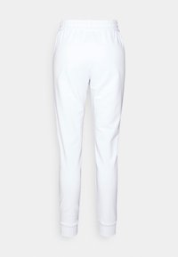 Vita sweatpants med elastisk midja och manchetter. Slät textur, smal passform, inga synliga mönster eller detaljer. Enkelt design.