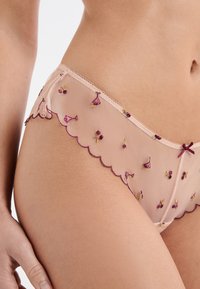 Bikini in rete color nudo con bordi smerlati, con ricamo floreale in rosa, viola e oro. Finitura delicata con un piccolo dettaglio a fiocco.