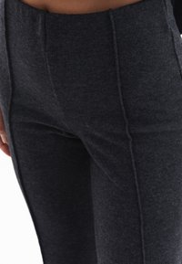 High-waisted, donkergrijze leggings van een zachte, gestructureerde stof met opvallende voornaad en zonder zichtbare zakken.