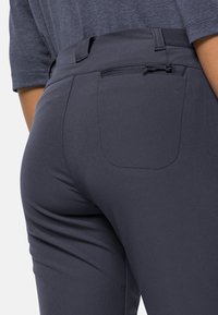 Pantaloni grigi elasticizzati caratterizzati da una texture liscia, una tasca posteriore con doppio cucitura e una vita regolabile con coulisse.